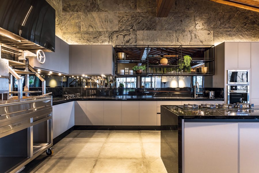 A cozinha (Florense Carlos de Carvalho) equipada com cooktop, churrasqueira e fitas de LED que valorizam o mobiliário sob medida