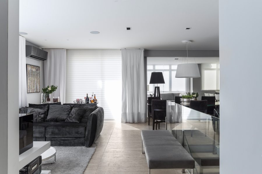Living integrado à cozinha da Florense possui sofás em veludo cinza, mesa de centro e luminária de piso Victoria,.