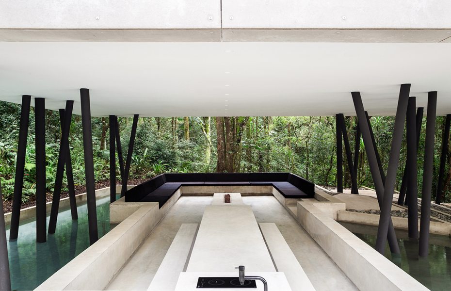 O lounge externo conta com lareira, mesa e bancos de concreto aparente