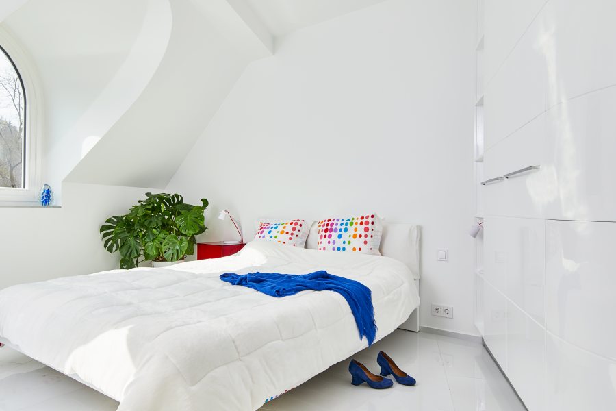 A suíte do primeiro andar ganhou mobiliário branco com detalhes coloridos nas almofadas, manta e vegetação.