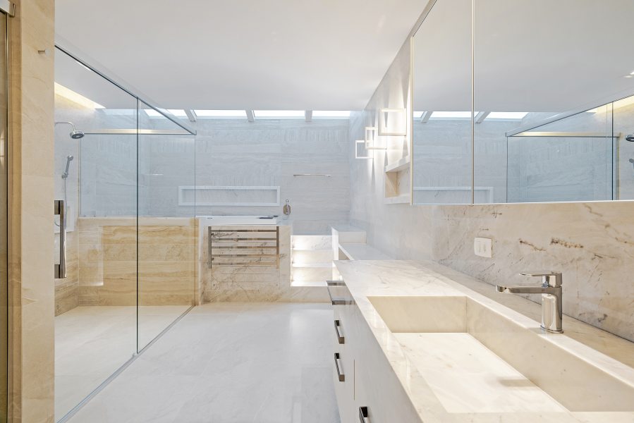A sala de banho do casal com 35m2, com mobiliário da Artigiano, é um local de relaxamento e setorizado com duchas e cubas individuais, compondo entre o Mármore Branco Piguês e o Navona