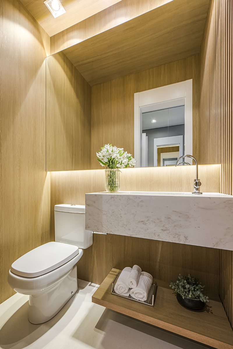 O lavabo foi totalmente revestido com painéis de madeira, executado pela Todeschini Batel, e reflete o conceito do empreendimento de integração com a natureza. O espelho recebeu iluminação com fitas de LED, proporcionando um cenário intimista