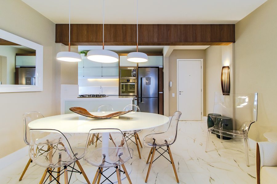 A madeira aparece no revestimento da viga que separa a sala da cozinha, na base da luminária de piso, e na arandela do hall de entrada (Grey House)