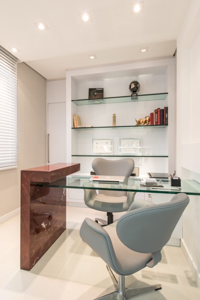 O escritório possui detalhe em mármore Bordeaux e mesa em vidro, para maior leveza, com prateleiras também em vidro