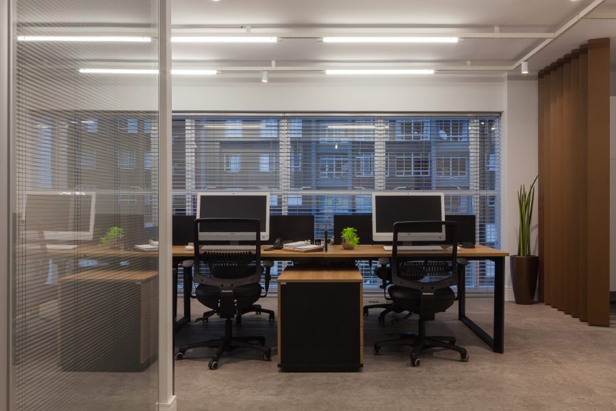 Na área de trabalho, piso vinílico tipo cimento queimado 90x90 e iluminação aparente imprimem aspecto industrial ao espaço.