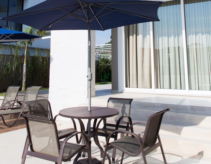 A área posterior da casa conta com deck e piscina, além de ombrelones e móveis próprios para áreas externas