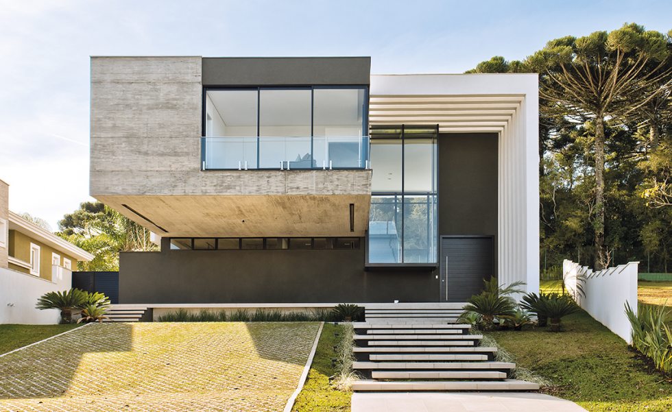O hall externo é desenhado por pergolados que complementam o volume principal da casa, criando um efeito de luz e sombra durante o dia. O volume em concreto moldado in loco pela Construtora MG estende-se até a parte posterior da residência e acomoda a área íntima da casa O hall externo é desenhado por pergolados que complementam o volume principal da casa, criando um efeito de luz e sombra durante o dia. O volume em concreto moldado in loco pela Construtora MG estende-se até a parte posterior da residência e acomoda a área íntima da casa