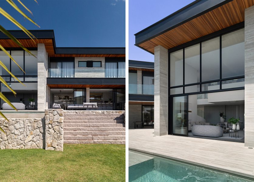 Na face posterior da casa, grandes esquadrias em alumínio preto integram os espaços internos ao jardim e à área de lazer. A base da residência, revestida em pedra moledo, reforça a sensação de solidez e cria o contraponto entre os volumes leves e o embasamento robusto.