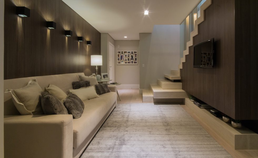 A entrada social do apartamento tem madeira como recurso de conforto acústico e visual.