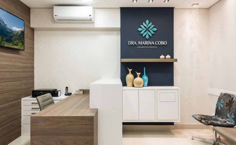 Na recepção, marcenaria sob medida (AD Marcenaria) em MDF Branco Diamante Cristall, da Duratex, e Zurich, da Masisa. O painel que leva a logomarca foi pintado com a cor Azul Noturno, da Suvinil Na recepção, marcenaria sob medida (AD Marcenaria) em MDF Branco Diamante Cristall, da Duratex, e Zurich, da Masisa. O painel que leva a logomarca foi pintado com a cor Azul Noturno, da Suvinil