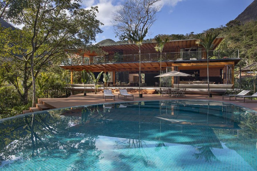 A arquitetura interaje com a natureza ao redor, seja pela inserção do volume no terreno, seja pelas grandes aberturas e vidros, trazendo o verde para o interior da casa. Grandes beirais e varandas espaçosas ajudam a minimizar a incidência térmica, reduzindo a necessidade de ar-condicionado. 
