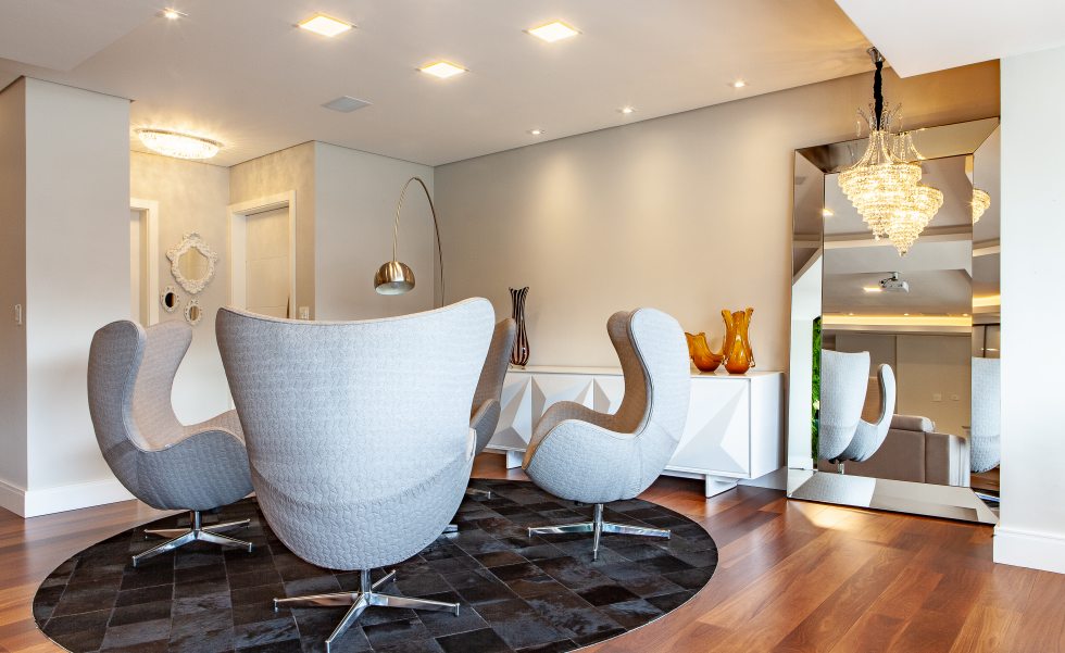 O estar recebeu cadeiras giratórias que também se comunicam com o home theater. O brilho do pendente em cristal (Grey House) é potencializado pelo espelho ao lado do buffet. O estar recebeu cadeiras giratórias que também se comunicam com o home theater. O brilho do pendente em cristal (Grey House) é potencializado pelo espelho ao lado do buffet.