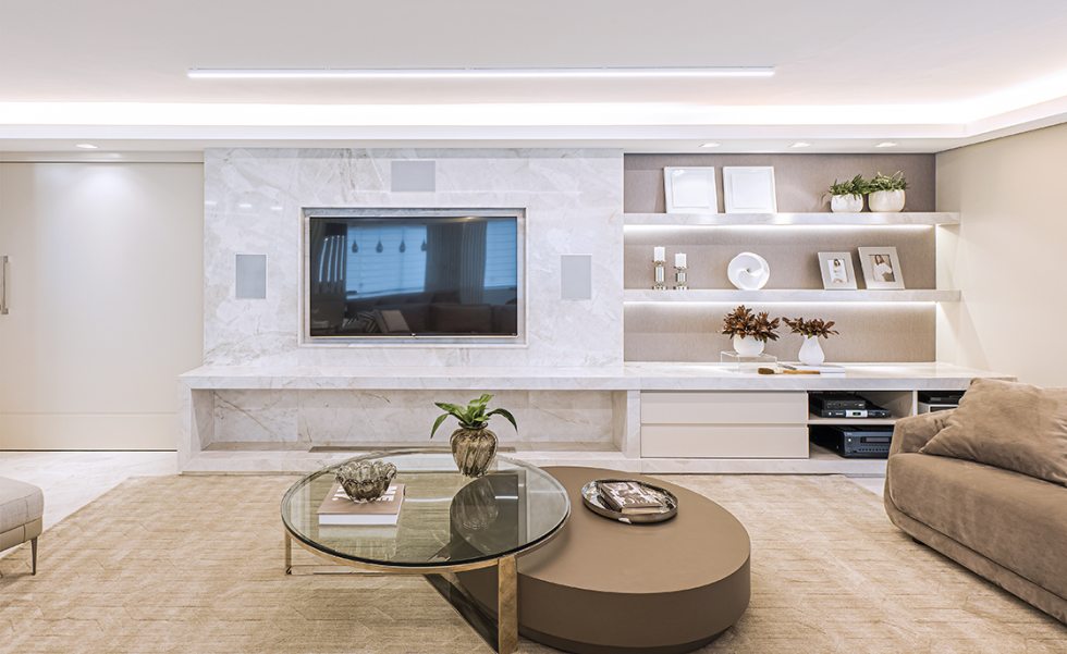 Após a reforma, o apartamento ganhou uma única área social integrada, com iluminação automatizada (Euro Audio). Para que ficassem discretamente ocultas do todo, caixas de som brancas foram embutidas no painel de mármore da mesma cor. Na lateral direita, nichos com os equipamentos de som e imagem, fornecidos também pela Euro Audio Após a reforma, o apartamento ganhou uma única área social integrada, com iluminação automatizada (Euro Audio). Para que ficassem discretamente ocultas do todo, caixas de som brancas foram embutidas no painel de mármore da mesma cor. Na lateral direita, nichos com os equipamentos de som e imagem, fornecidos também pela Euro Audio