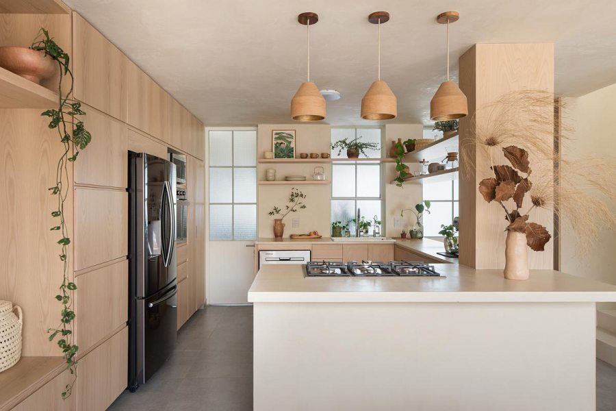 Cozinha com toques artesanais: revestimentos naturais e objetos em cerâmica reforçam a estética sensorial do projeto.