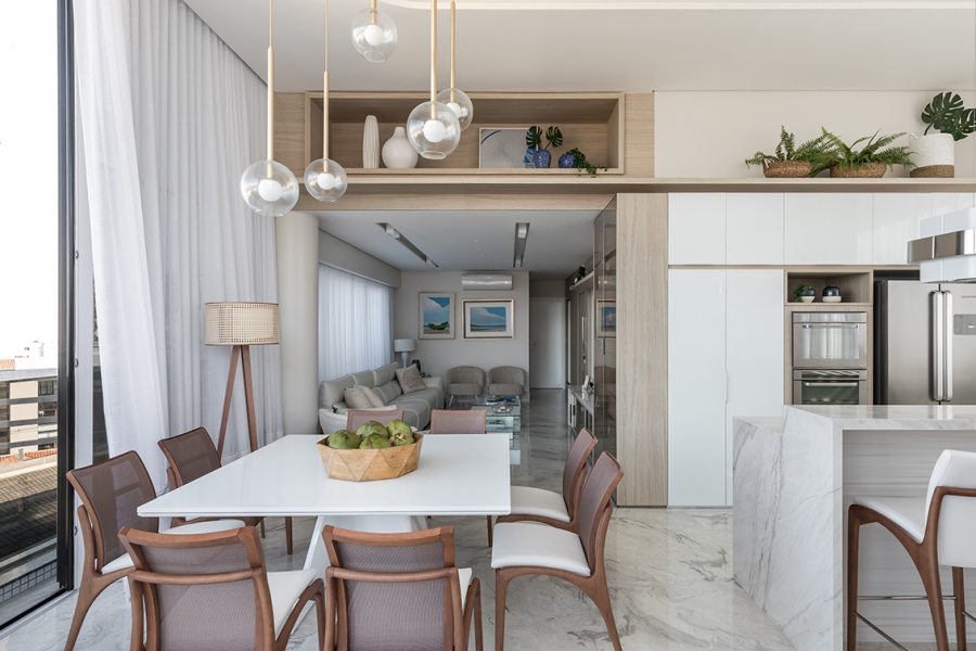 No primeiro pavimento da cobertura, o trabalho com o forro de gesso em duas alturas permitiu realçar o pé-direito da sala de jantar e cozinha. O layout integrado e os móveis sob medida da Deco Marcenaria eliminaram obstáculos à ventilação e iluminação naturais.