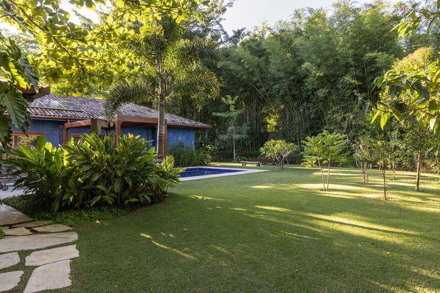 Implantação inteligente: A casa térrea em formato de “L” foi posicionada no ponto mais baixo do terreno, respeitando a vegetação existente.