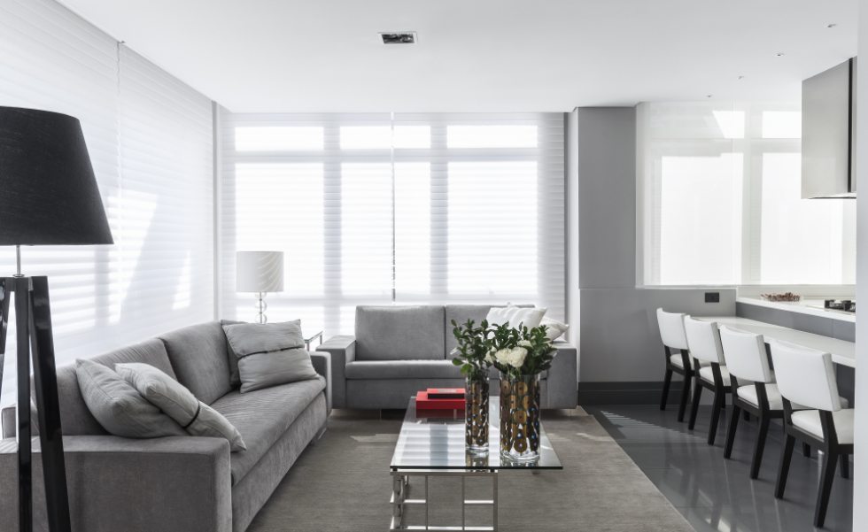 Na foto, o living integrado à cozinha com sofás em veludo cinza