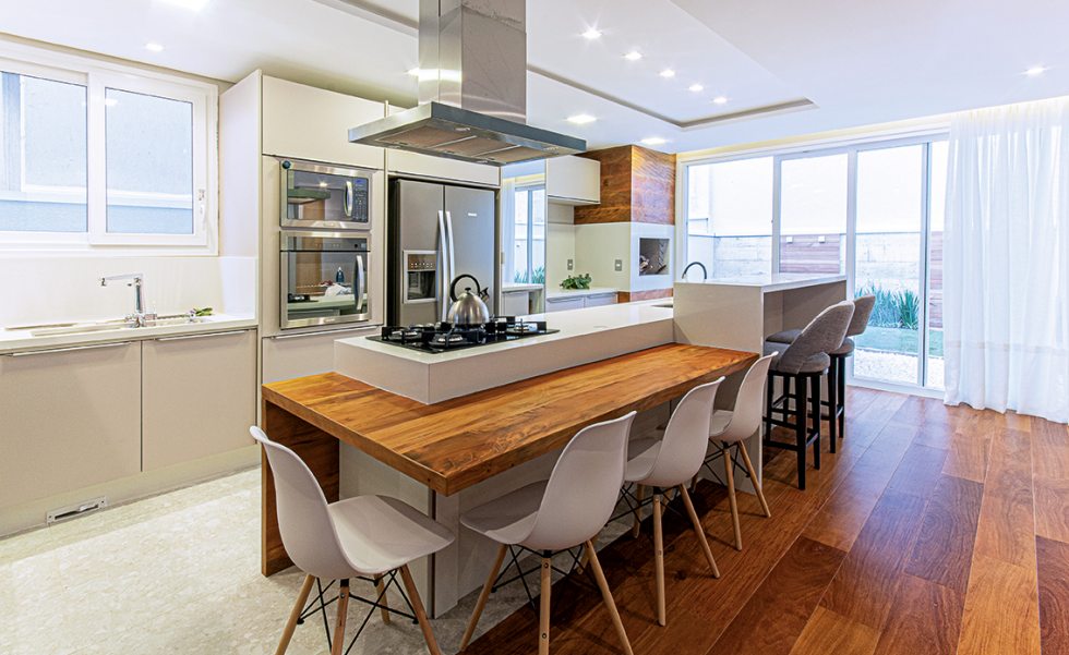 Na cozinha gourmet, marcenaria sob medida com tampos personalizados de madeira maciça e silestone branco nas bancadas Na cozinha gourmet, marcenaria sob medida com tampos personalizados de madeira maciça e silestone branco nas bancadas