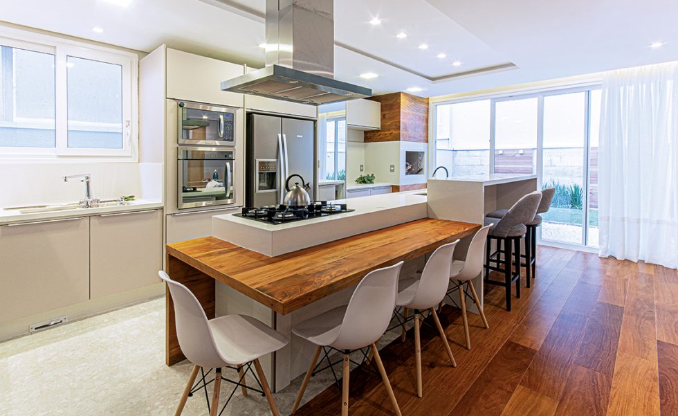 Na cozinha gourmet, marcenaria sob medida com tampos personalizados de madeira maciça e silestone branco nas bancadas