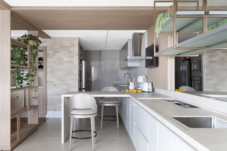 A cozinha recebeu bancada de pedra natural, prateleiras em madeira, eletros embutidos e banquetas da Sierra.