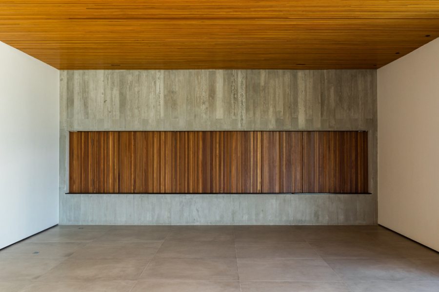 Uma ampla janela de madeira cumaru se abre para um lindo jardim e permite a entrada de abundante luz natural