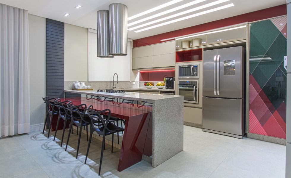 cozinha gourmet recebeu bancada em granito Branco Itaunas, porcelanato de cimento cinza acetinado e mobiliário executado em MDF. A mesa vermelha em laca que ladeia a bancada foi pintada tinta Sayerlack. A porta do armário se destaca pelo adesivo 3D com motivos geométricos cozinha gourmet recebeu bancada em granito Branco Itaunas, porcelanato de cimento cinza acetinado e mobiliário executado em MDF. A mesa vermelha em laca que ladeia a bancada foi pintada tinta Sayerlack. A porta do armário se destaca pelo adesivo 3D com motivos geométricos