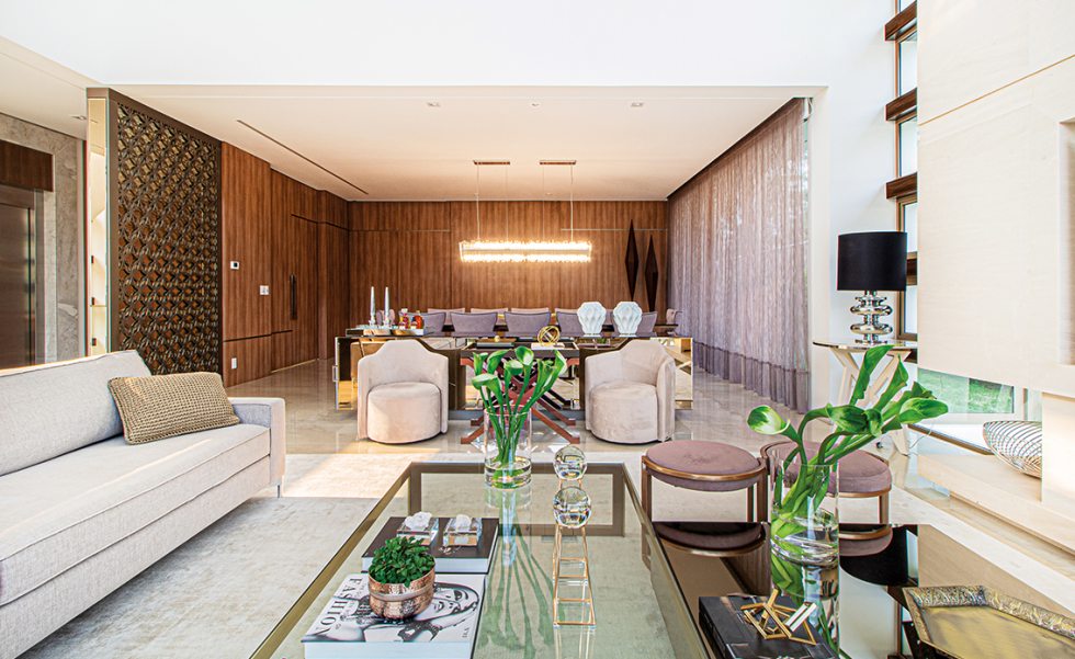 No living integrado com jantar, o pendente de cristal traz sofisticação e brilho ao ambiente, compondo com a mesa de jantar toda em espelho bronze da M. Decor No living integrado com jantar, o pendente de cristal traz sofisticação e brilho ao ambiente, compondo com a mesa de jantar toda em espelho bronze da M. Decor