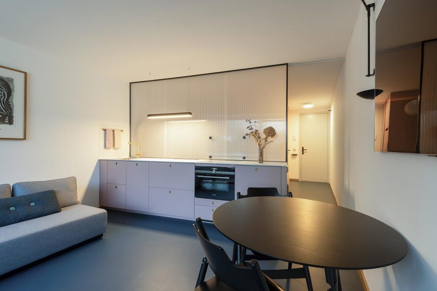 Uma única luminária sobre a bancada resolve a tarefa e dá unidade visual à cozinha compacta. Projeto Studio Nea | Foto Hermann Rupp.