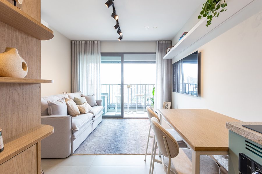 As arquitetas da Freijó Arquitetura optaram por manter a porta de correr da sala mesmo com o envidraçamento da sacada. Desta forma, os moradores podem reduzir o ruído externo enquanto assistem TV na sala | Foto: Mariana Camargo.