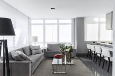 Living integrado à cozinha Florense com sofás em veludo cinza, mesa de centro e luminárias de piso Victoria