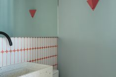 A bancada esculpida ganha formato recuado e sob medida no lavabo.