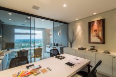 O escritório é dividido por um painel de vidro, criando ambientes com leveza e elegância. 