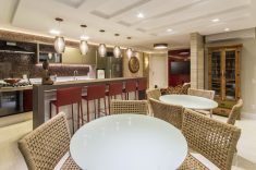 A ampla sala de jantar com cozinha gourmet possui duas mesas com tampo em vidro (Artezanalle) e cadeiras de fibra (Tidelli), para conforto total dos convidados. 