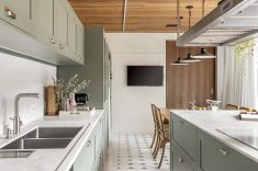 O piso em ladrilho hidráulico, a bancada em mármore Branco Paraná e os metais em inox escovado compõem a cozinha. 