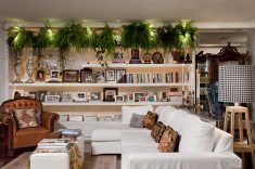A sala de estar com sofás e poltronas ganha uma luxuosa estante com plantas para conectar com a natureza.