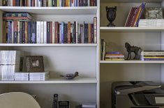 Para a composição do décor dessa estante, a arquiteta aproveitou diversos objetos trazidos de viagens, além de um acervo literário composto por livros herdados dos pais, exemplares adquiridos em momentos especiais ou presenteados por pessoas queridas. Essa conjunção deixa o ambiente elegante e, ao mesmo tempo, aconchegante | Foto: Carlos PiratiningaNessa sala de estar integrada com a varanda, Cristiane Schiavoni valorizou a presença da cristaleira, móvel que simboliza o início da vida e uma das primeiras conquistas do casal de moradores. Na leitura do décor contemporâneo, sua tonalidade combinou com os demais tons incorporados ao projeto | Foto: Luis Gomes