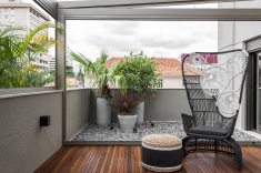 O terraço recebeu cobertura de vidro com estrutura metálica, deck em madeira Itaúba, poltrona Catarina e pufe artesanal. Ao fundo, palmeira reca, palmeira leque, bromélias e clúsias compõem o pequeno jardim. Com a inclusão dos terraços o apartamento passou dos 75m² originais para 120m² de área privativa